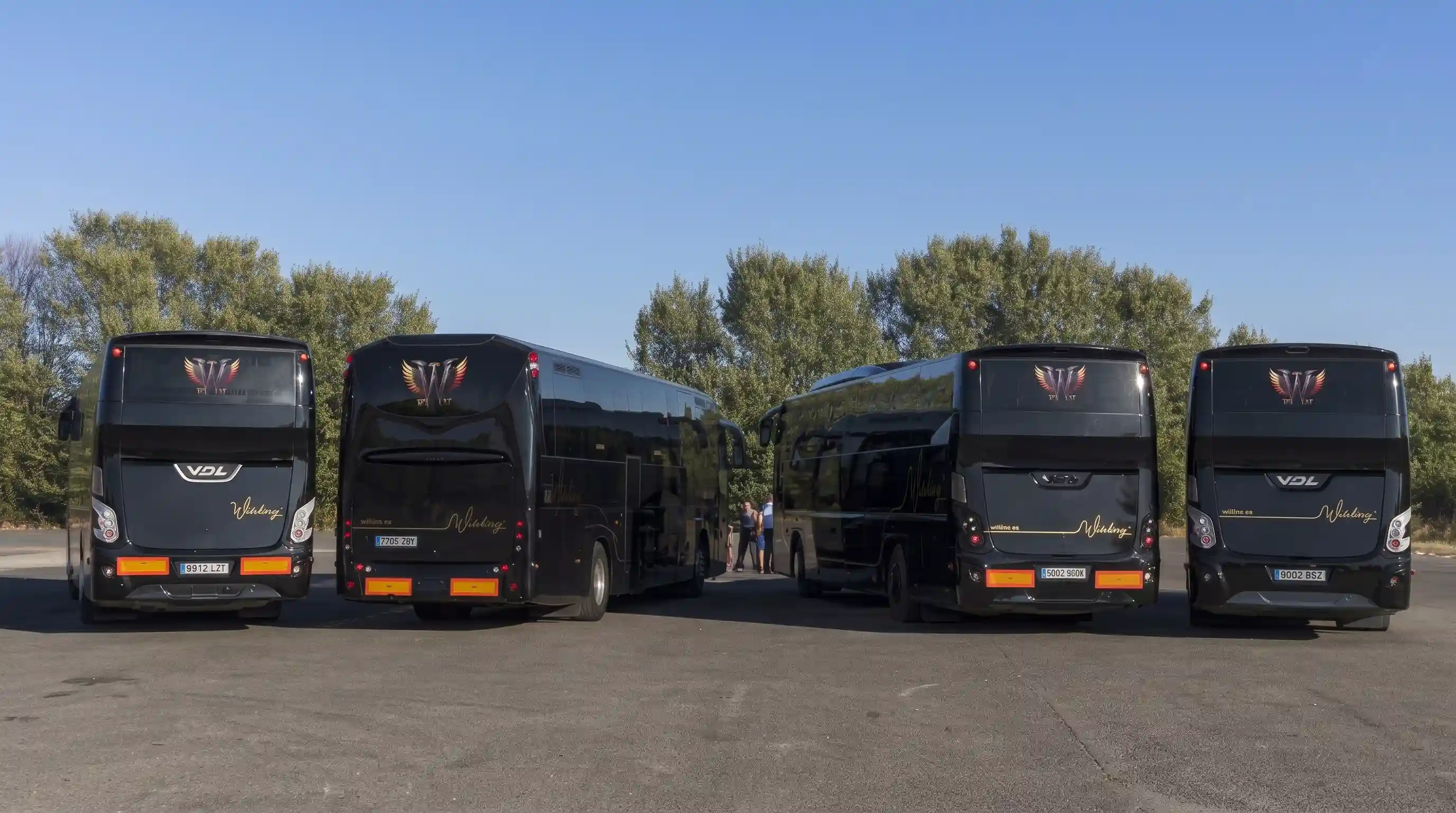 Cuatro autocares VDL negros de Winking Bus aparcados juntos en una explanada, dos de frente y dos de espaldas